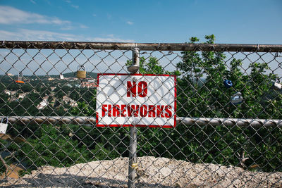 Information sign by chainlink fence against sky