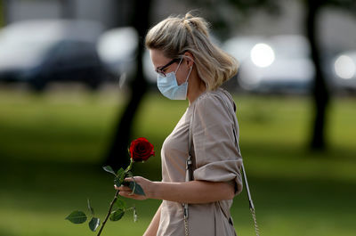 Woman holding red while standing by plant