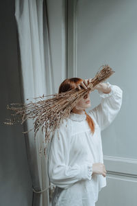 Woman with red hair with her face covered by flowers