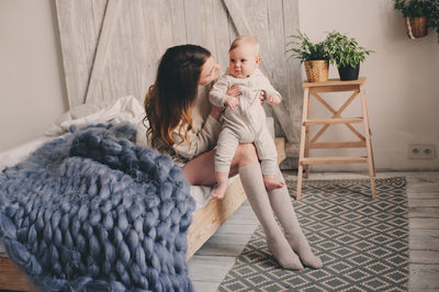 Mother and daughter sitting on sofa at home