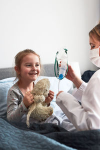 Doctor examining smiling girl at home