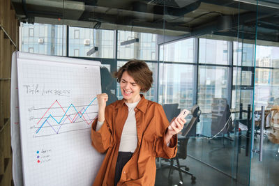 Portrait of young woman standing in office