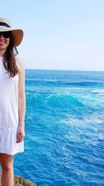 Beautiful woman standing by sea against sky