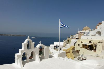 Greece flag in city by sea against clear sky