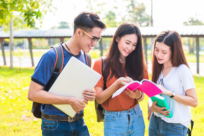 Friends studying while standing at park