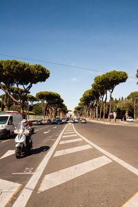 Road by trees against clear sky