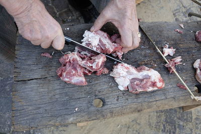 Midsection of butcher cutting meat on wood