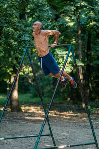 Full length of shirtless man exercising in park