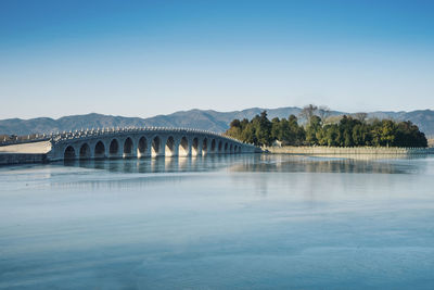 Arch bridge over river against clear sky