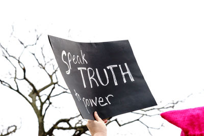 Cropped hand holding text on placard in city during protest