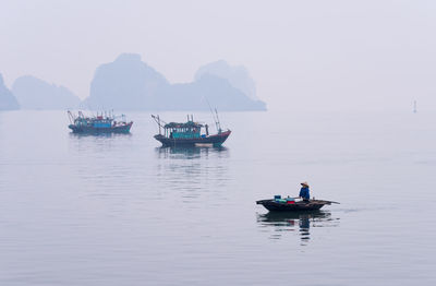 Woman on boat in sea against sky during foggy weather