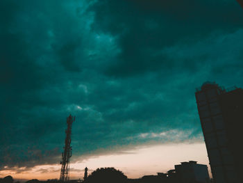 Low angle view of smoke stack against sky at sunset