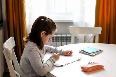 Side view of girl studying at home