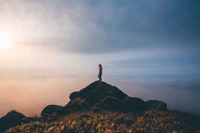 Man standing on rock against sky