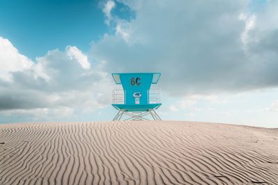 Information sign on sand at beach against sky