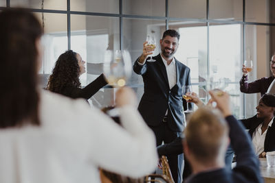 Cheerful male and female toasting wineglasses during office party