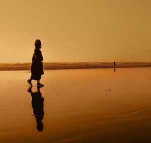 Full length of man standing on beach during sunset