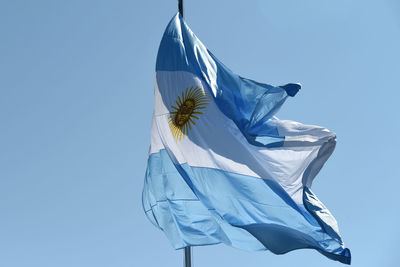 Low angle view of flag against clear blue sky