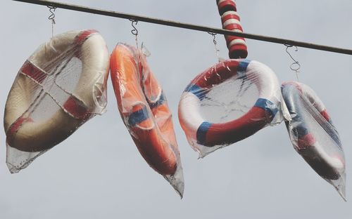 Close-up of lifebuoy hanging on rope against sky