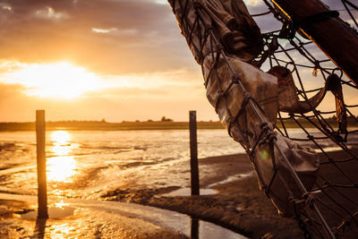 Wooden post on beach against sky during sunset