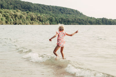 Girl enjoying at beach against cliff