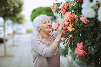 Elderly woman admiring beautiful bushes with colorful roses