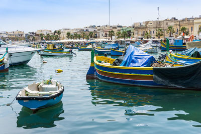 Boats moored at harbor against sky