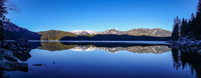 Scenic view of lake and mountains against clear blue sky