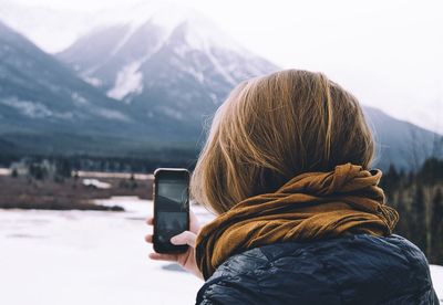 Rear view of person photographing on mobile phone