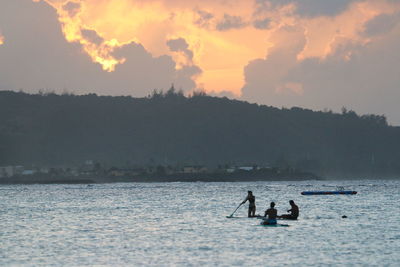 Silhouette people on boat against sky during sunset