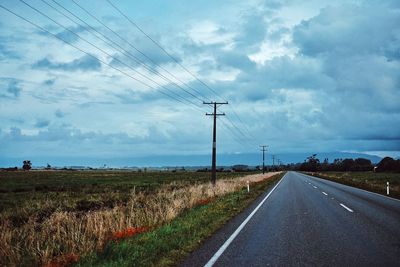 View of field against cloudy sky