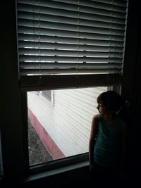 Woman looking through window at home