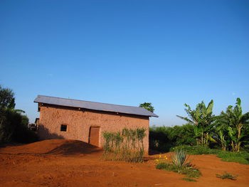 House on field against clear blue sky