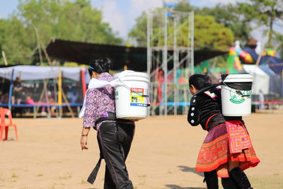 Rear view of friends standing at park