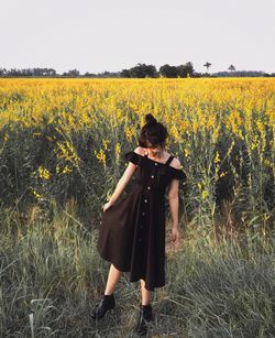 Woman standing on field with yellow flowers