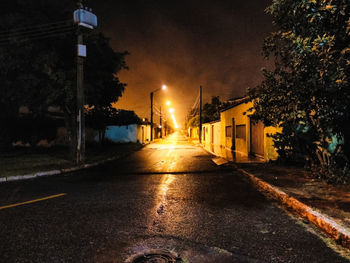 Illuminated street amidst buildings in city at night