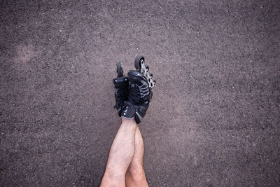 Low section of man sitting with roller skates on land