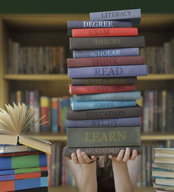 Girl holding stacked books in library