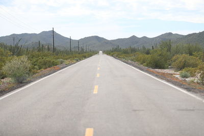 Road leading towards mountains against sky