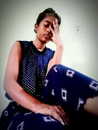 Mid adult woman sitting against wall at home