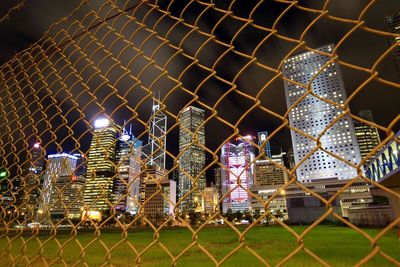 Illuminated chainlink fence against sky at night