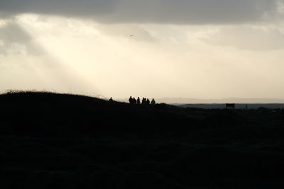Silhouette of people on landscape against sky