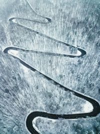 Aerial view of winding road amidst snow covered trees in forest during winter