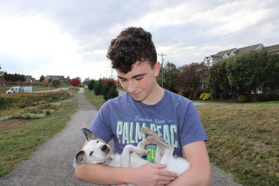 Portrait of young man with dog against sky