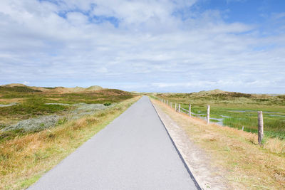 Empty road along grassy field