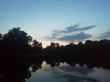 Silhouette trees by lake against sky during sunset