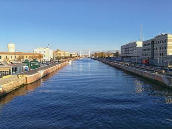 View of river in city against clear blue sky