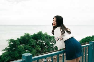 Young woman looking at sea against sky