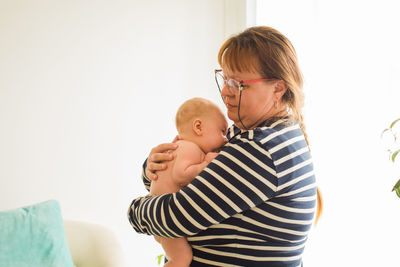 Side view of mother carrying daughter at home