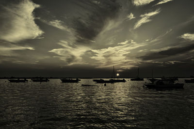 Sailboats in sea against sky at sunset